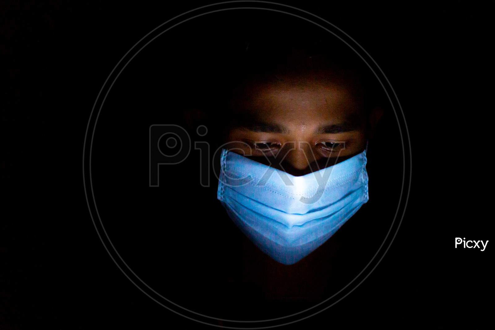 A Blue Surgical Mask-Wearing Young Man Was Playing Smartphone Games At Dhaka.