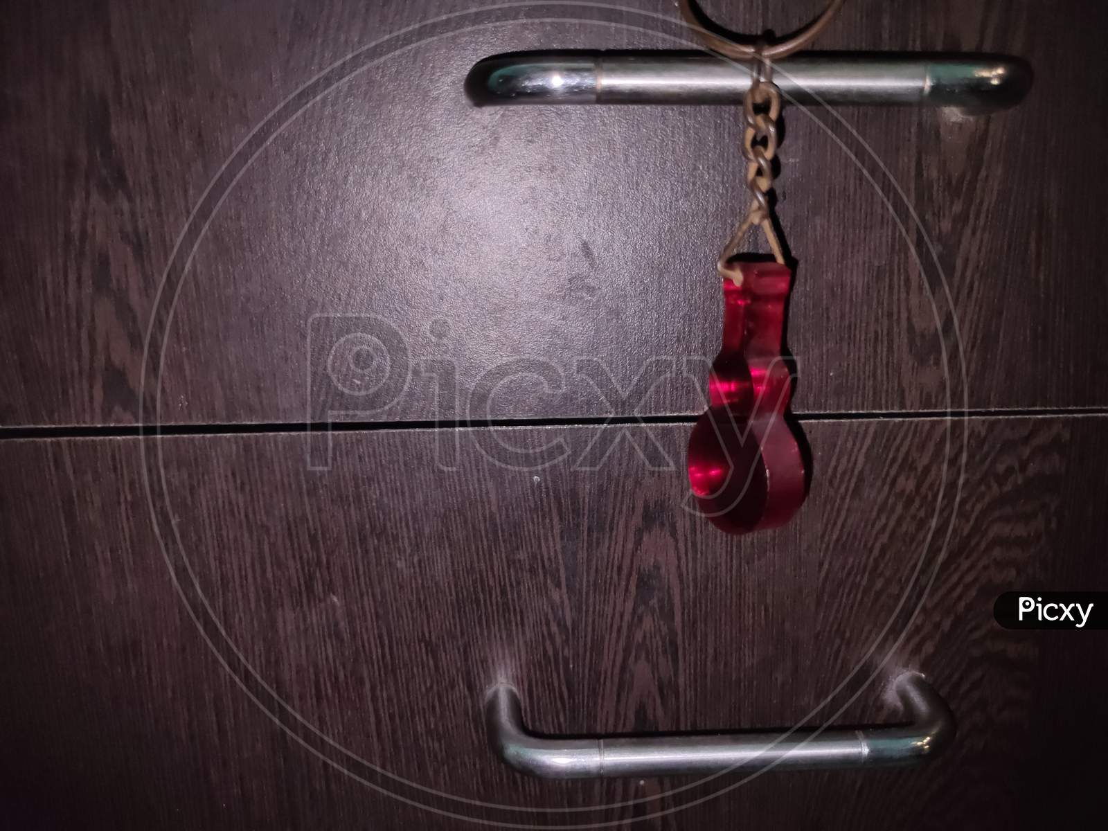 A Hanging Red Guitar Key-Chain In Low Light Condition