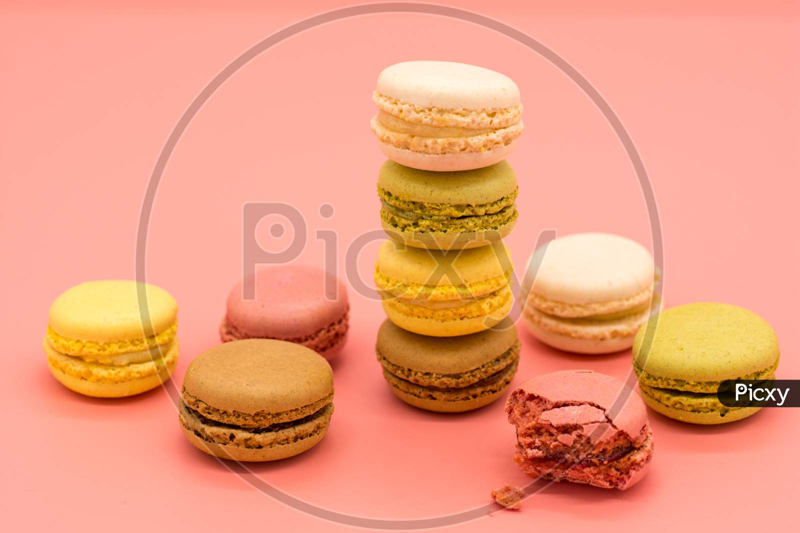 delicious macarons full and bitten and crumbs arranged on colored background