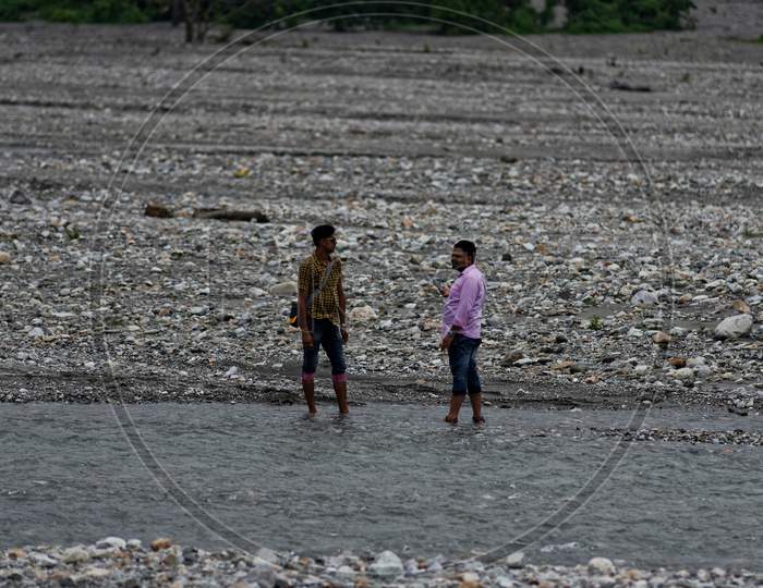 Indian people are walking by the pebbles beside the river bank of a dried river bed. Indian lifestyle