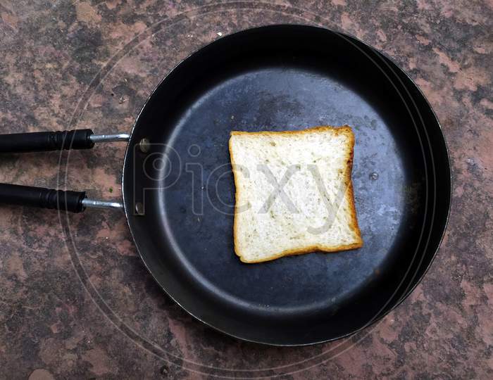 A WHITE BREAD PUT IN A  BLACK FRY PAN ON STONE BACKGROUND