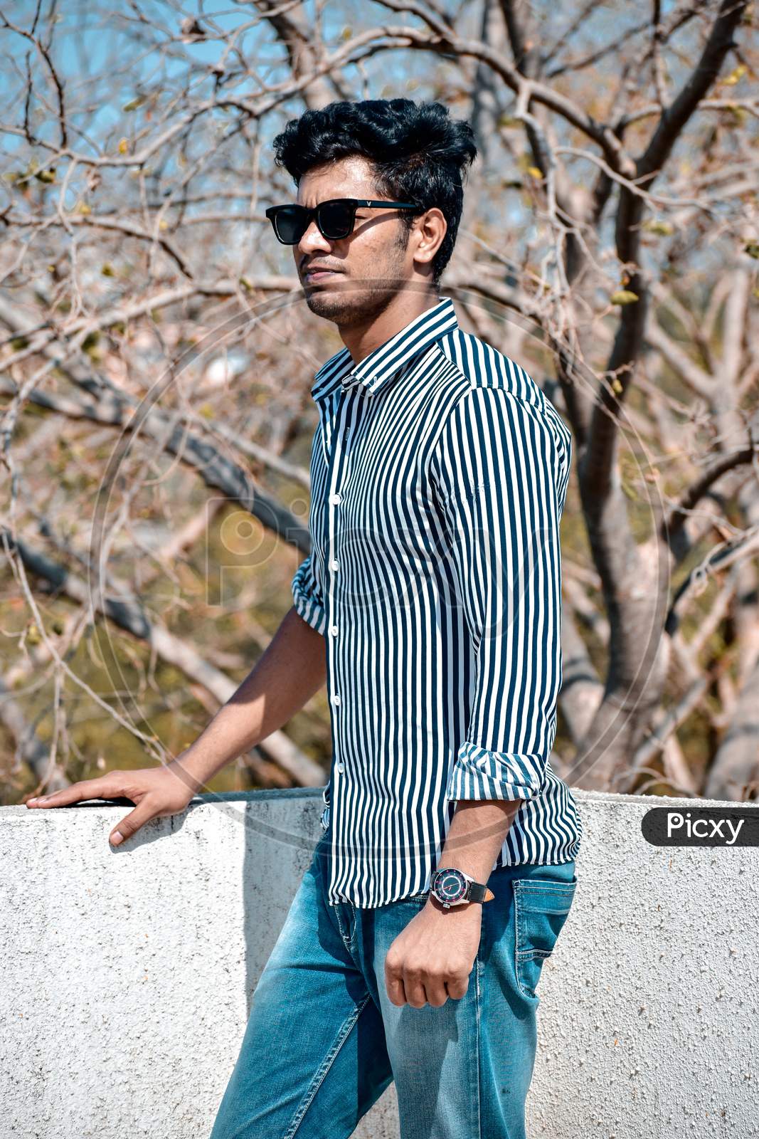 Stylish man standing for a photoshoot wearing sunglasses
