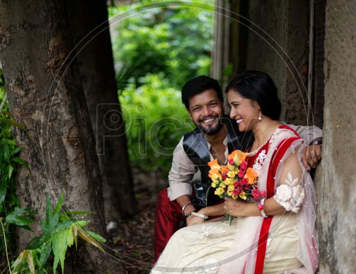 Young and attractive Indian Bengali brunette couple sharing romantic moments in front of a vintage house window wearing Indian traditional ethnic cloths. Indian lifestyle and fashion