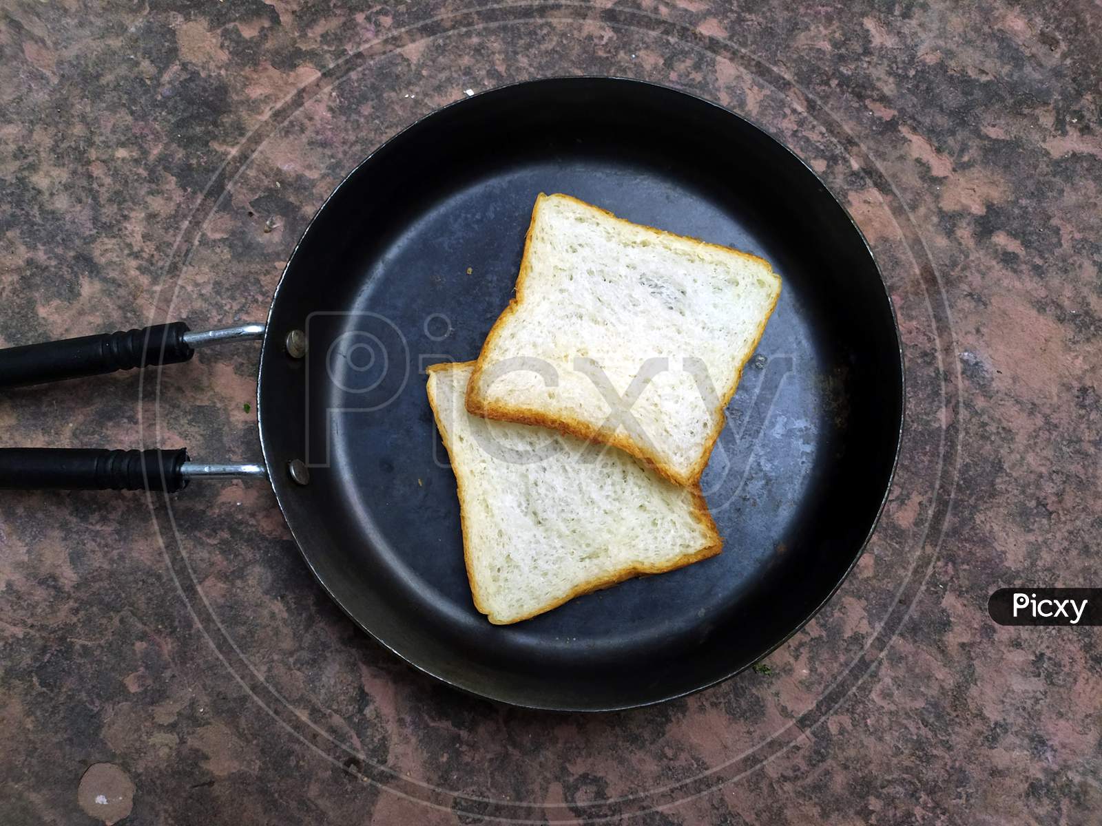 A WHITE BREAD PUT IN A  BLACK FRY PAN ON STONE BACKGROUND