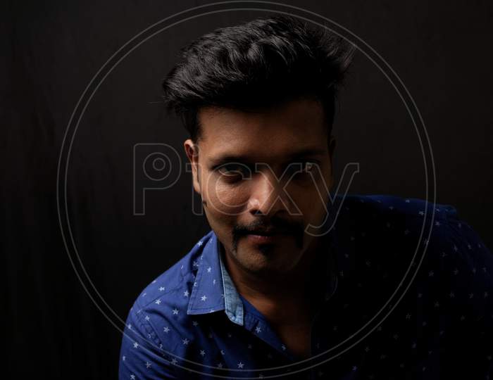 Close up portrait of a handsome and intelligent Indian brunette man in his specs wearing blue shirt with white stars. Indian lifestyle and fashion portrait
