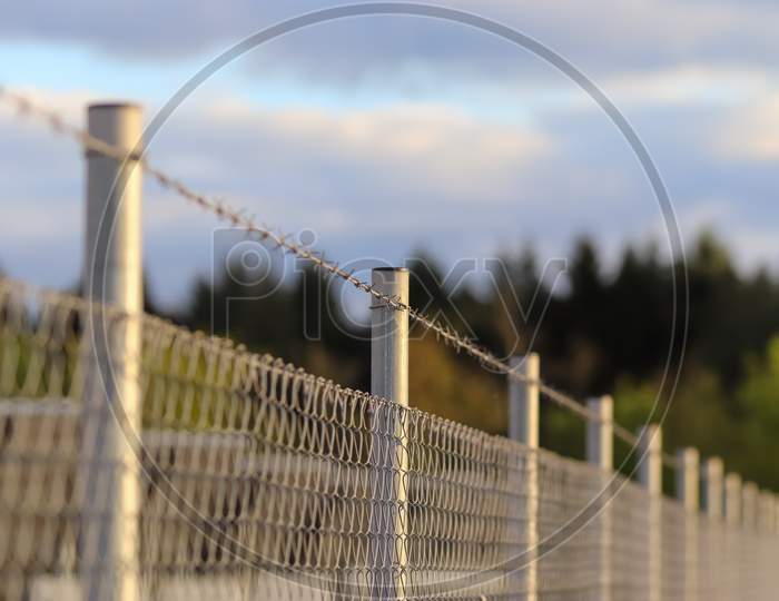 Close up view on barbed wire on a field with a soft bokeh in the background