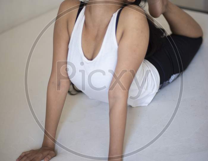 Indian brunette girl performing yoga/sports /exercise in sportswear in front of a white background. Indian lifestyle