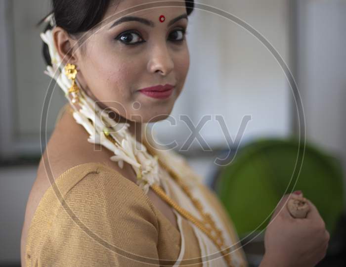 Portrait of an young and attractive Indian woman in white traditional wear with colorful flowers in hands for the celebration of Onam/Pongal in white background. Indian lifestyle