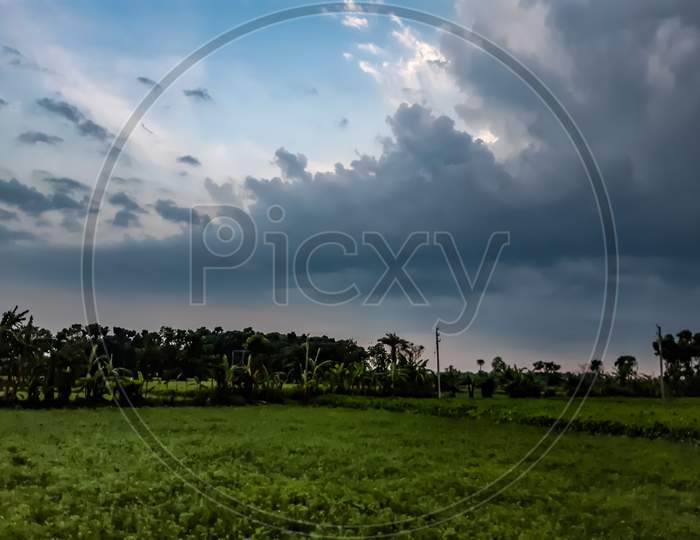Farmland And Sunlight In Rural India At Sunset, Images Of Black Clouds In The Red Sky.