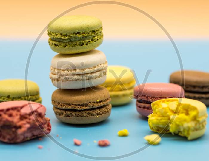 delicious macarons full and bitten and crumbs arranged on colored background