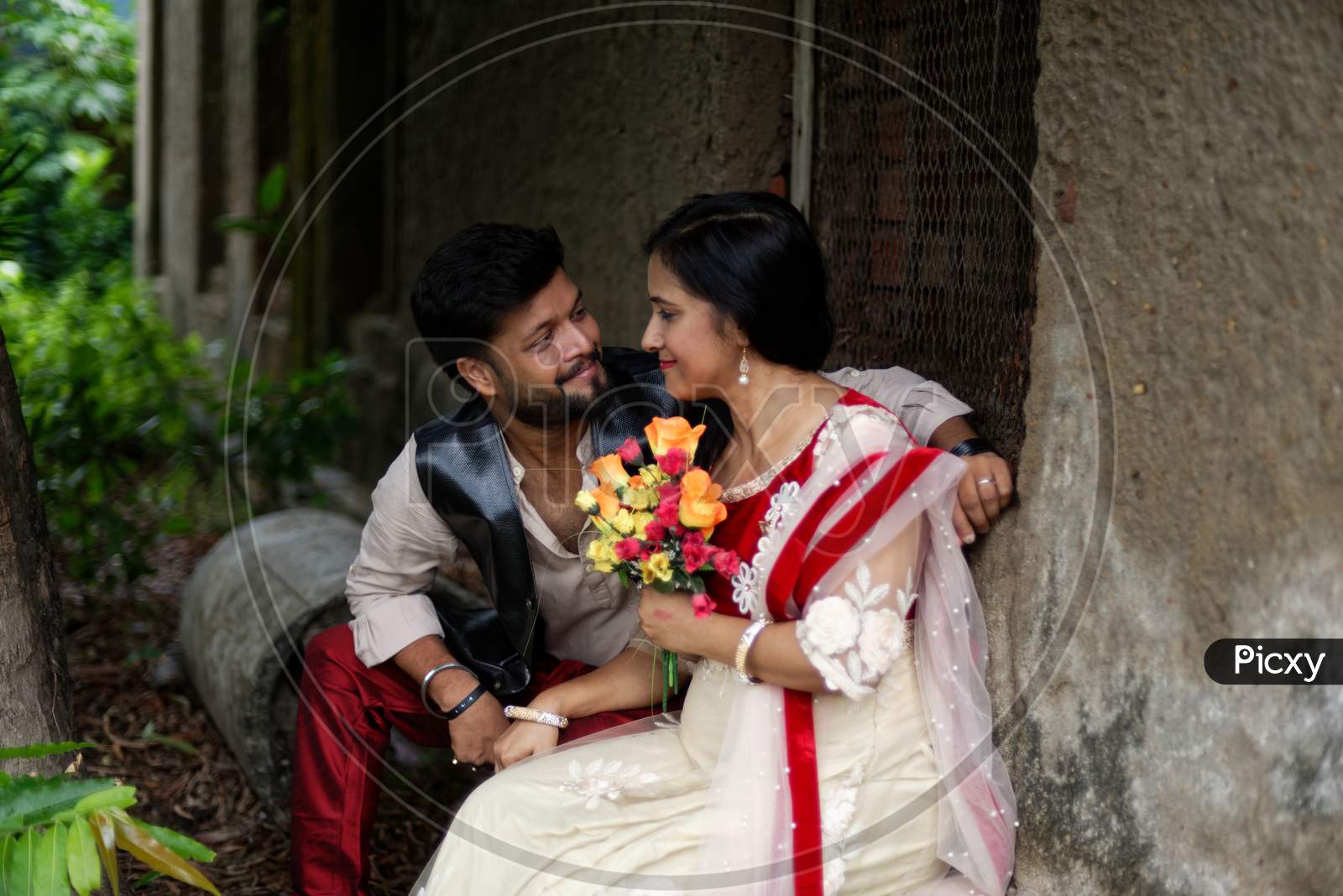 Young and attractive Indian Bengali brunette couple sharing romantic moments in front of a vintage house window wearing Indian traditional ethnic cloths. Indian lifestyle and fashion