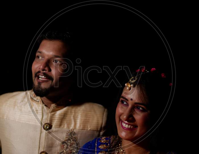 Young and beautiful Indian Gujarati couple in Indian traditional dress celebrating Diwali with diyas/lamps on the terrace in darkness on Diwali evening. Indian lifestyle and Diwali celebration