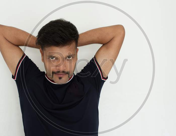Close up portrait of a handsome and intelligent Indian brunette man wearing a solid black t shirt standing before a copy space white background. Indian lifestyle and fashion portrait