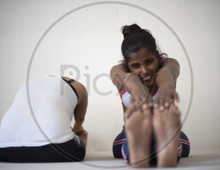 Indian dark skinned brunette girl performing yoga/sports /exercise in sportswear in front of a white background. Indian lifestyle