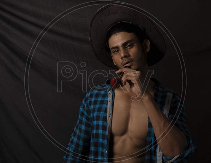 Portrait of an young and handsome brunette Bengali muscular man in open shirt  in front of black background. Indian lifestyle.