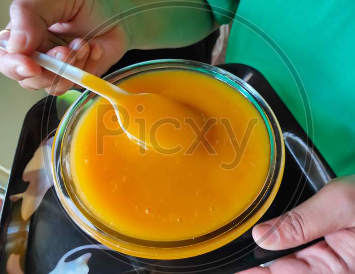 Mango juice in a bowl. Mango juice serving with spoon. Mango pulp with black background. Fresh juice of mango in a bowl.