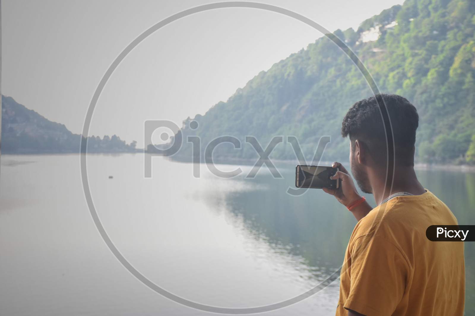 Nainital/India - May 7, 2020: boy clicking a photo of mountain and lake, in nainital