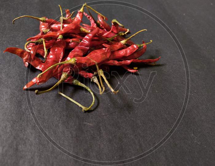 Whole dried red chilli on black background.