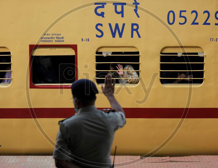 Men wave at Railway Protection Force (RPF) personnel as they travel in a train to Danapur, Bihar in a special train arranged by the government to repatriate migrant workers at the Chikkabanavara Junction Railway Station on the outskirts of Bangalore, India.