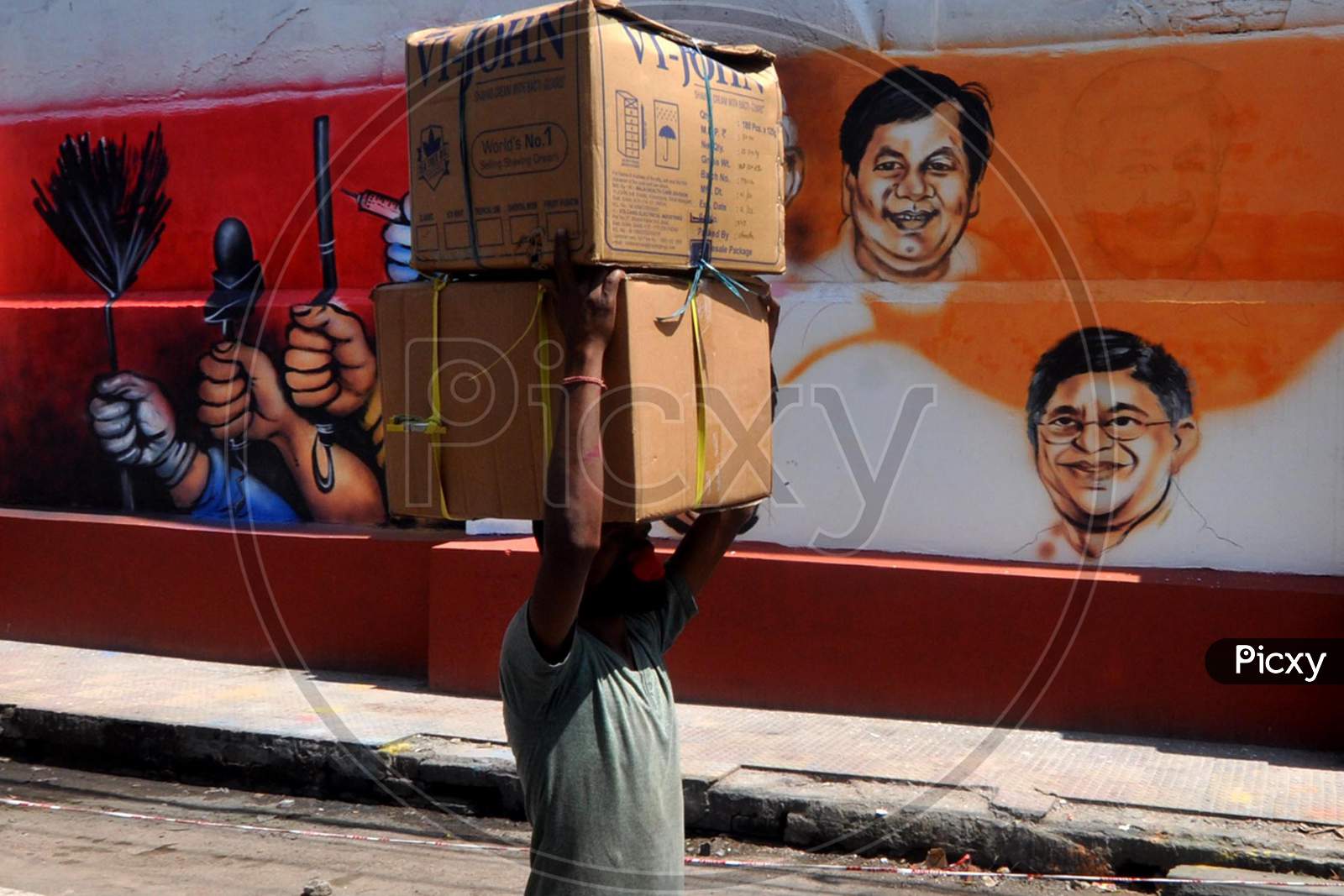 A Labourer Walks Past A Mural, During Nationwide Lockdown Amidst Coronavirus Or COVID-19 Pandemic , In Guwahati, Saturday, May 09, 2020.