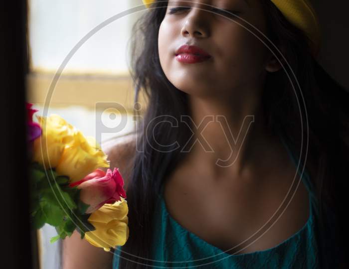 Fashion portrait of an young and attractive Indian Bengali brunette girl with blue western dress and yellow fashionable cap in front of black studio background. Indian fashion portrait and lifestyle
