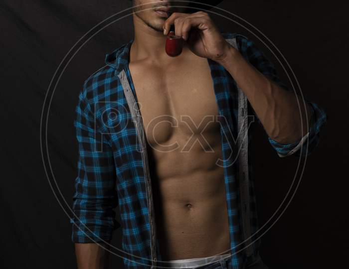 An young and handsome Indian Bengali brunette man with muscular body doing exercise in a room in white background. Fitness and Indian lifestyle.