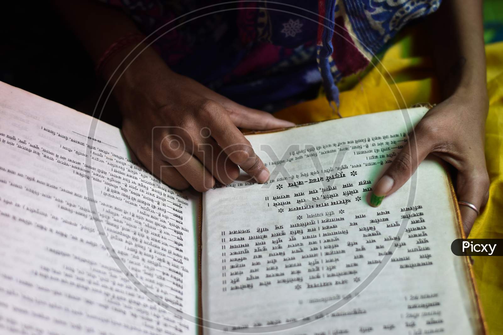 India - May 09, 2020: closeup of a Indian girl reading a holy ramayan and bhagwat geeta at home, with blur background.