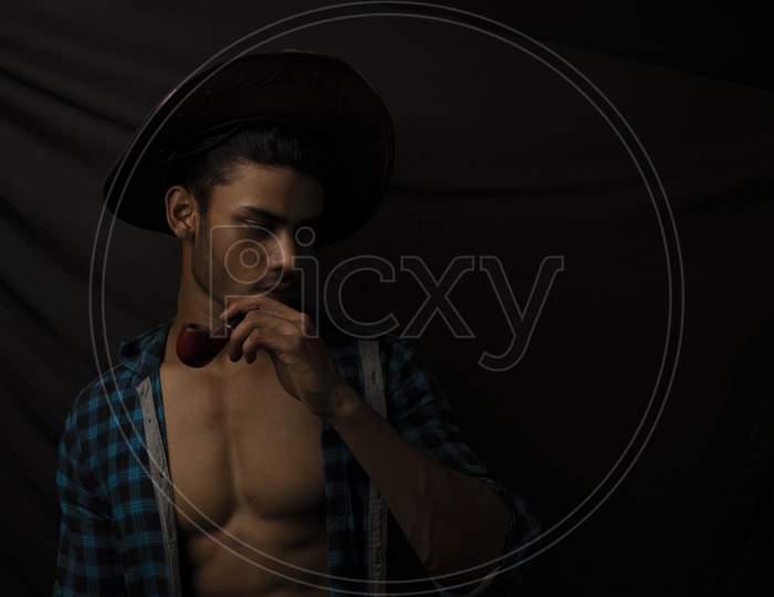Portrait of an young and handsome brunette Bengali muscular man in open shirt  in front of black background. Indian lifestyle.