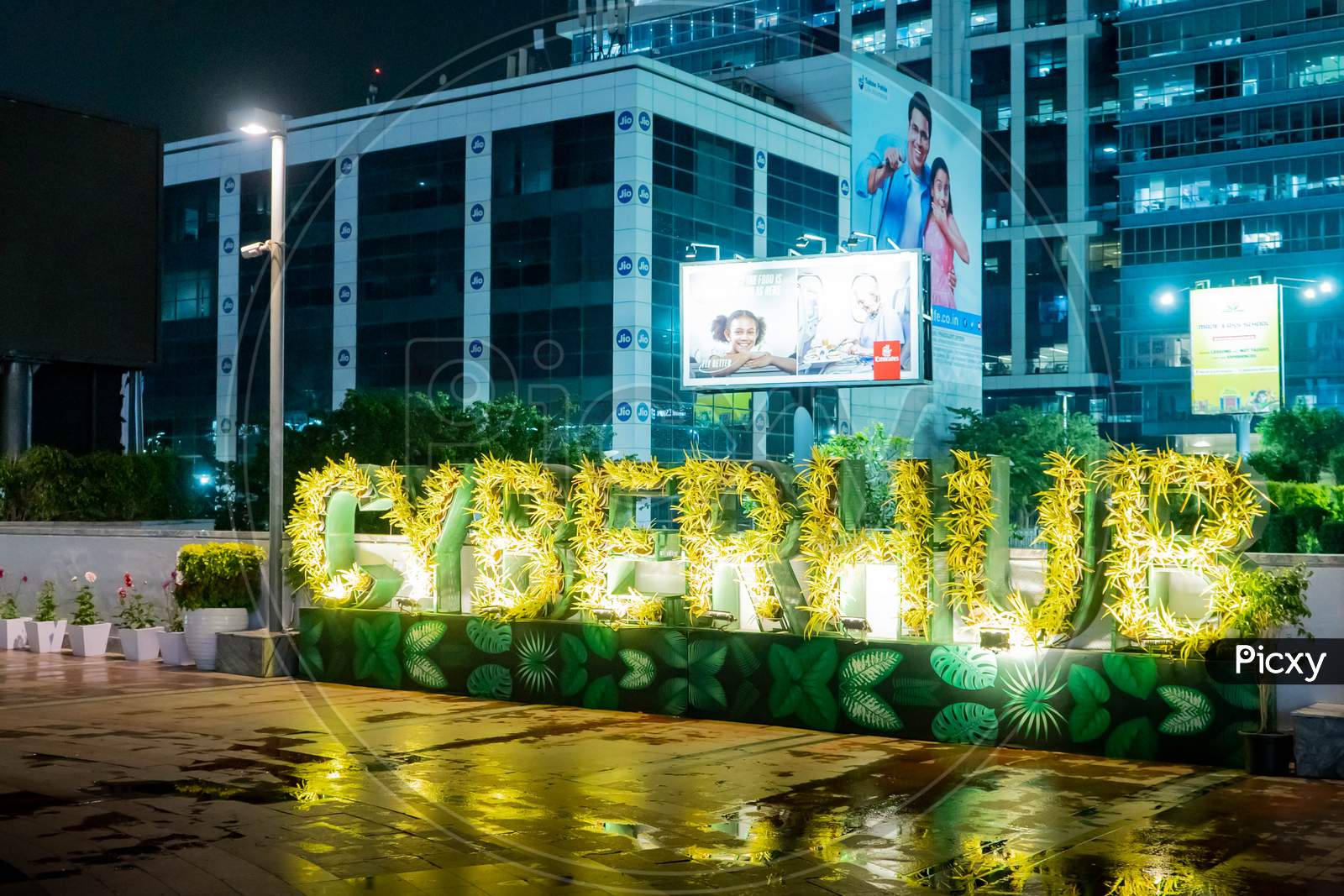 image-of-cyberhub-spelled-out-in-light-bulbs-set-on-plants-with-the-beautiful-lit-skyscrapers-of