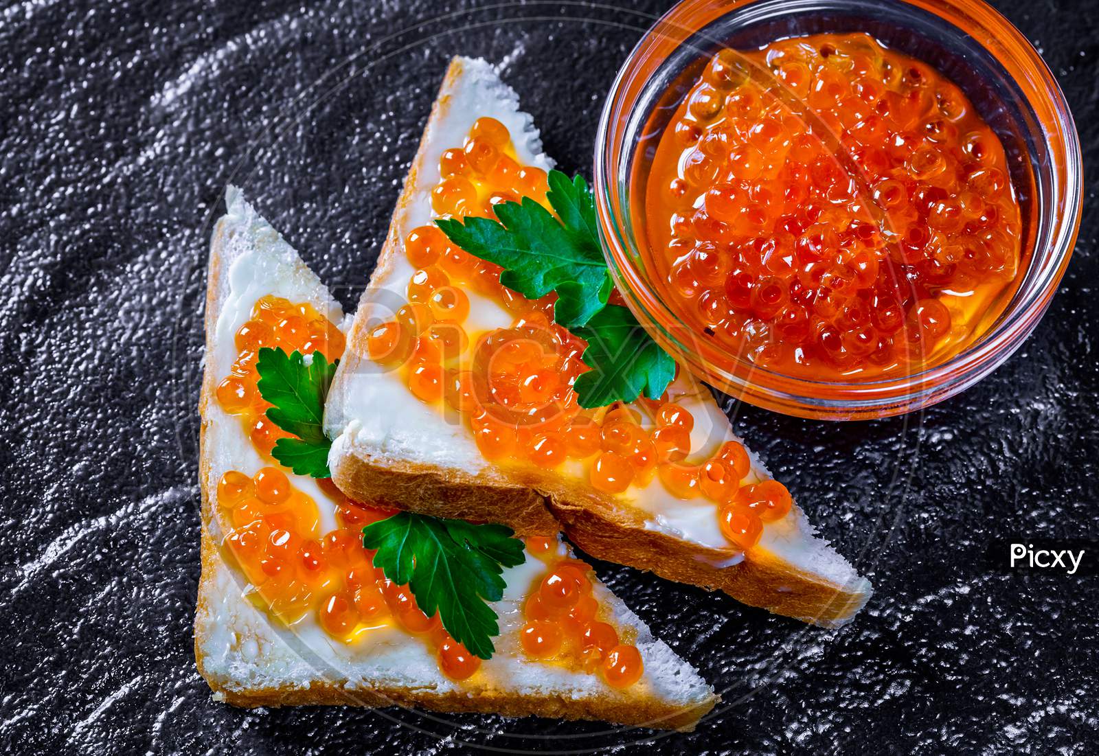 Red caviar in a glass bowl and on sandwiches
