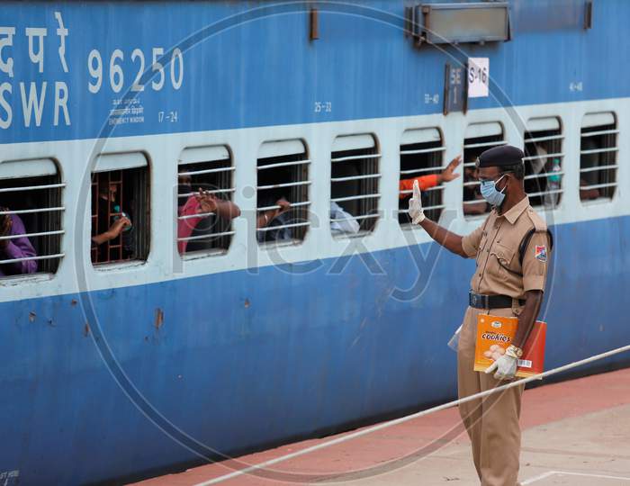 Men wave at Railway Protection Force (RPF) personnel as they travel in a train to Danapur, Bihar in a special train arranged by the government to repatriate migrant workers at the Chikkabanavara Junction Railway Station on the outskirts of Bangalore, India.