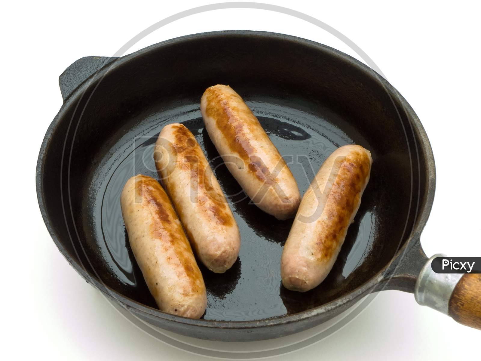 frying pan with four cooked sausages
