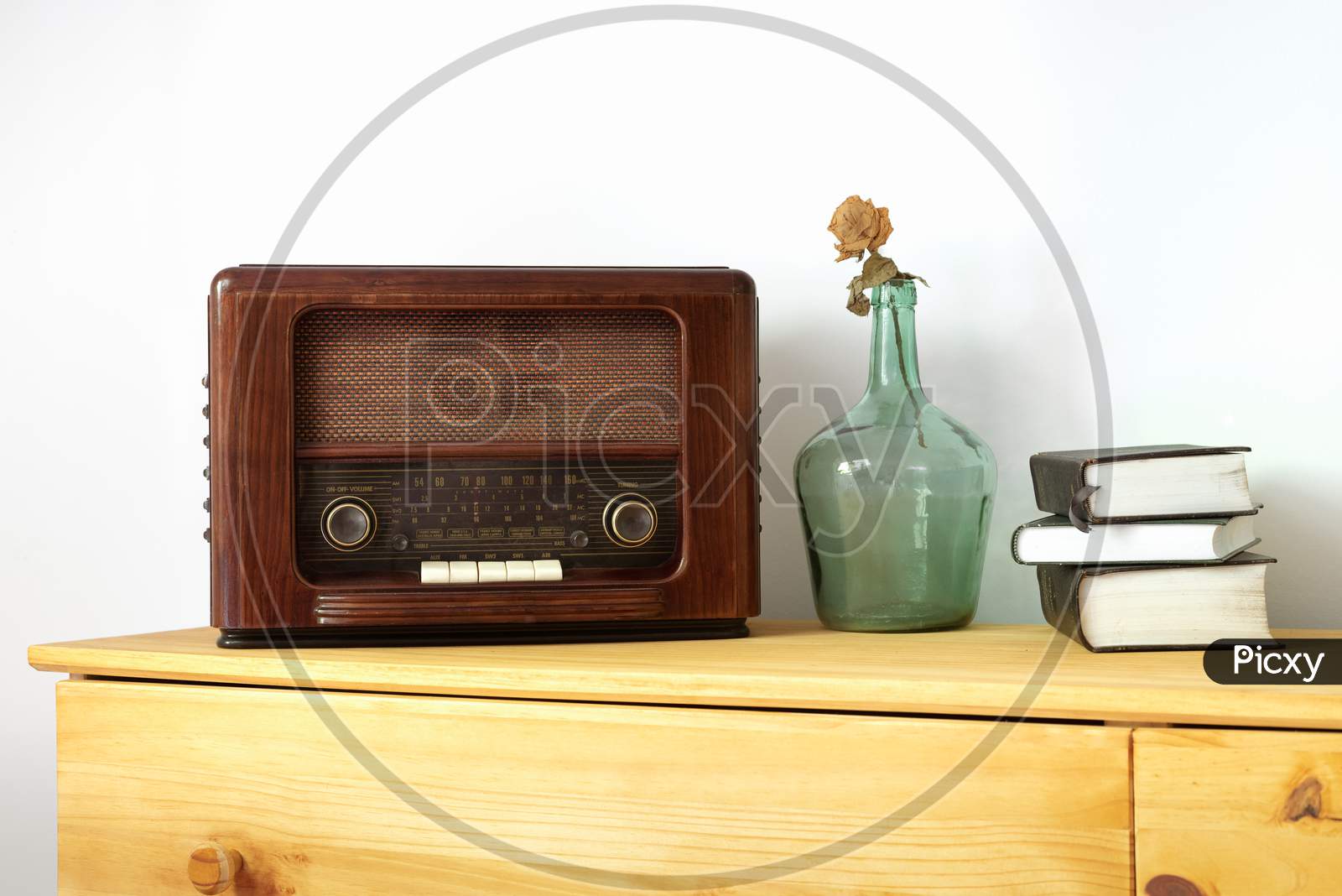 Vintage radio made of wood, green vase and old books on a table