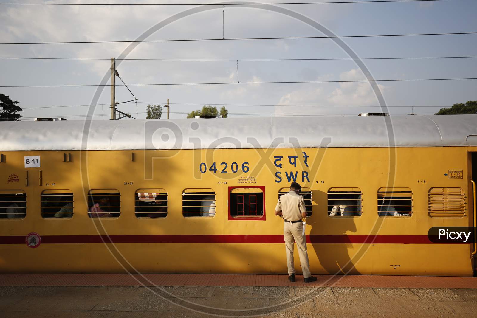 A Railway Protection Force (RPF) personnel checks travel documents of migrant workers travelling to Danapur, Bihar in a special train arranged by the government to repatriate migrant workers at the Chikkabanavara Junction Railway Station on the outskirts of Bangalore, India.