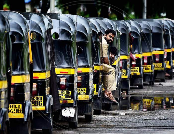 Auto rickshaws in line are parked parallel to one another