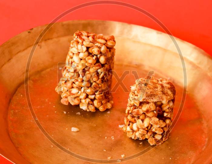 Indian Healthy Snack Made Of Jaggery, Puffed Rice And peanuts On an Isolated Red Background