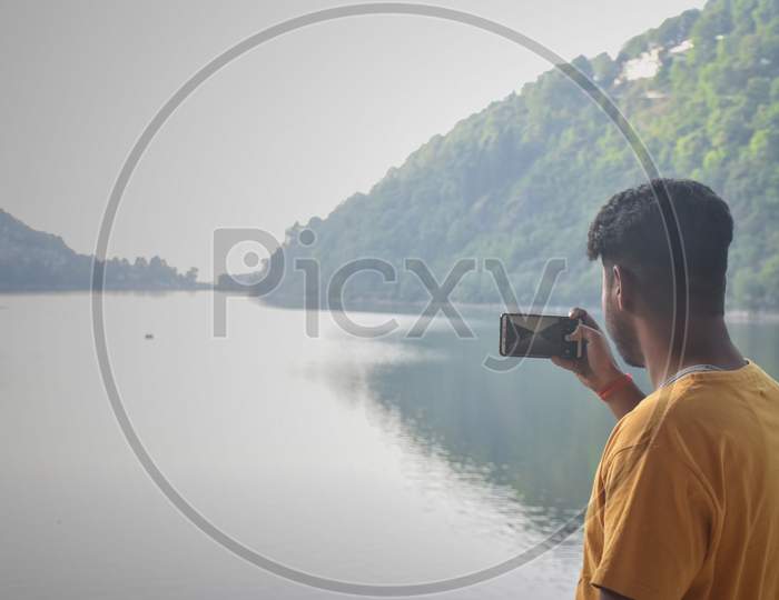 Nainital/India - May 7, 2020: boy clicking a photo of mountain and lake, in nainital