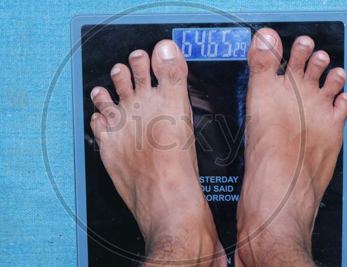 A MAN CHECKING HIS WEIGHT