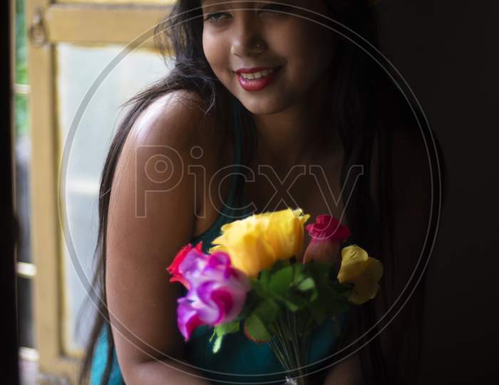 Fashion portrait of an young and attractive Indian Bengali brunette girl with blue western dress and yellow fashionable cap in front of black studio background. Indian fashion portrait and lifestyle