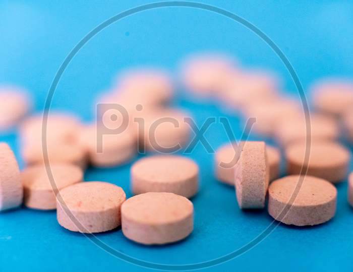 Selective Focus Shot Showing Tablets, On Blue Showing The Antiviral Cure For Coronavirus Covid19 Pandemic Ravaging The World