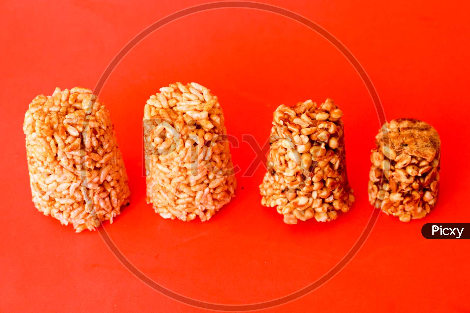 Indian Healthy Snack Made Of Jaggery, Puffed Rice And peanuts On an Isolated Red Background