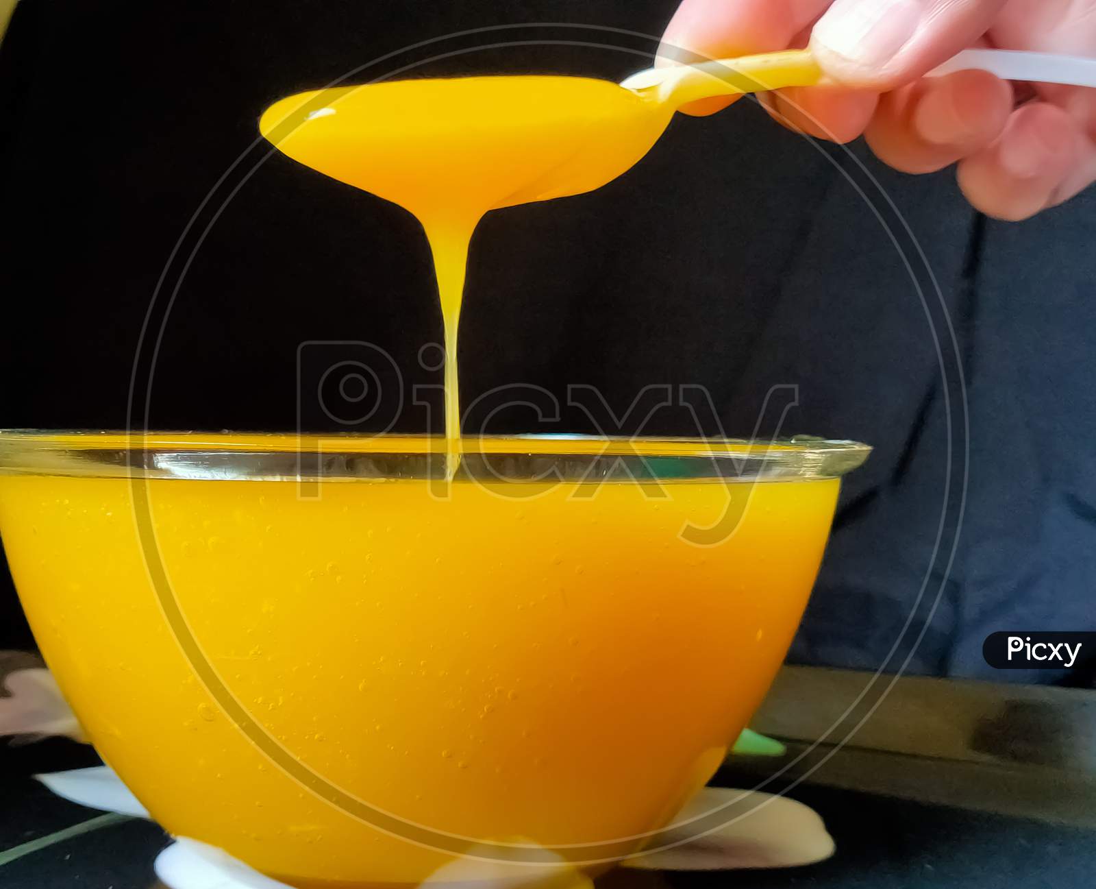 Mango juice in a bowl. Mango juice serving with spoon. Mango pulp with black background. Fresh juice of mango in a bowl.