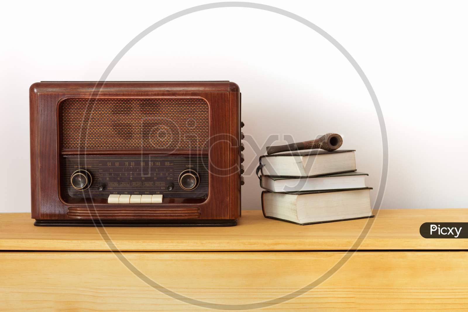 Vintage radio made of wood, old books and a pipe on a table
