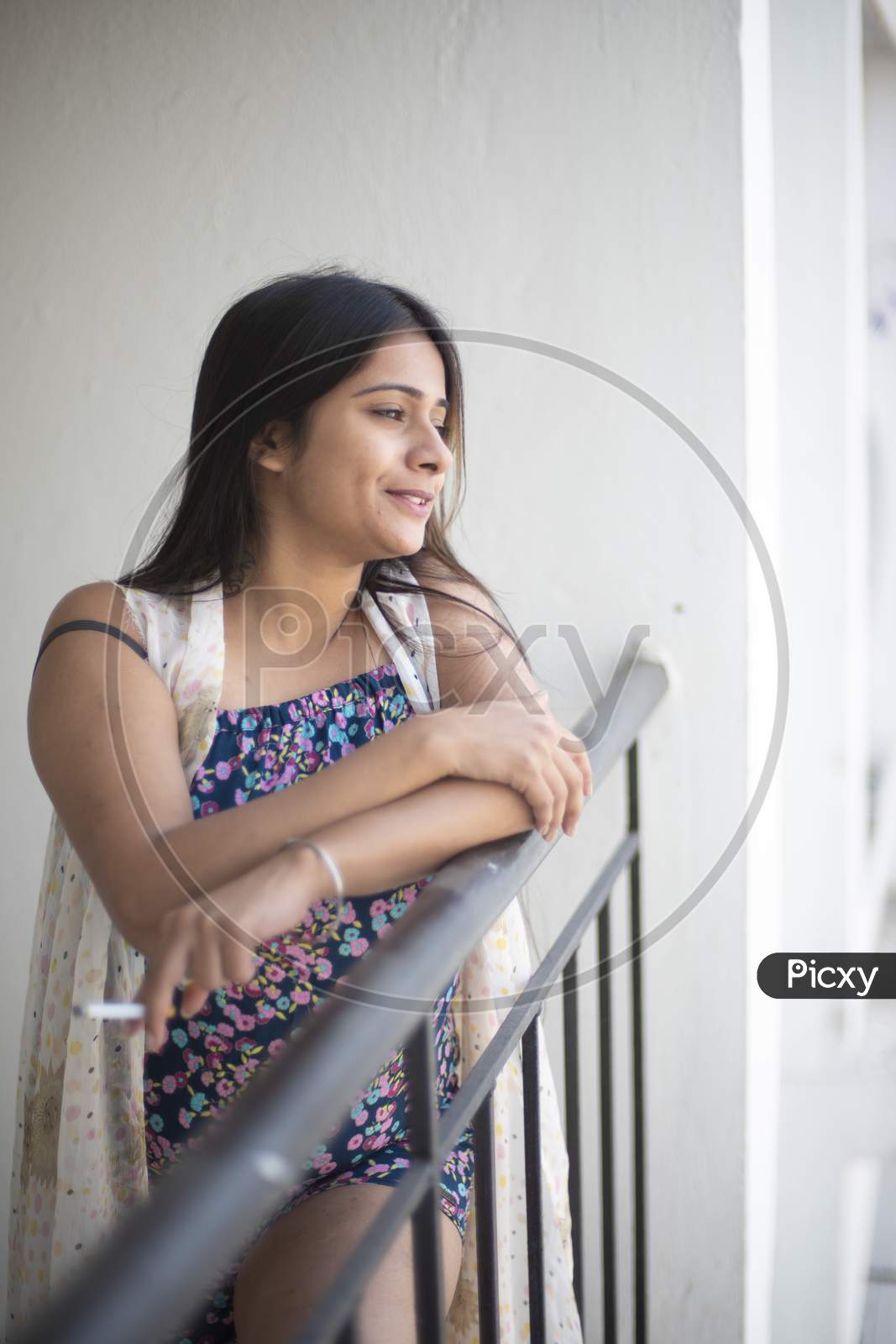 Image of An young and attractive Indian Bengali brunette woman in white  sleeping wear is smoking cigarette on the balcony in the morning in white  background. Indian lifestyle.-NA030135-Picxy