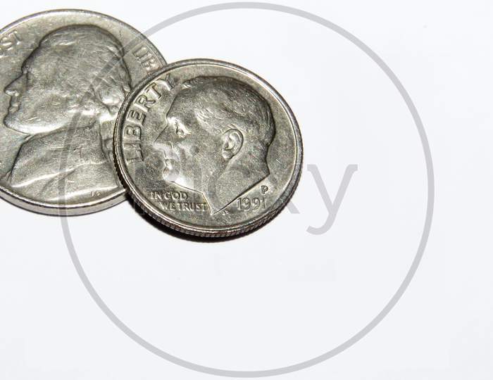 Dime and Nickel Coins together on White Background. The dime, in United States usage, is a ten-cent coin, and A nickel, in American usage, is a five-cent coin struck by the United States Mint.