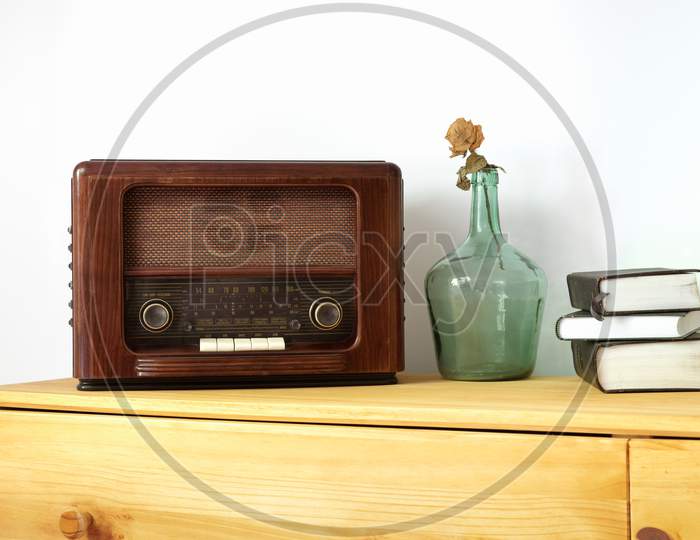 Vintage radio made of wood, green vase and old books on a table