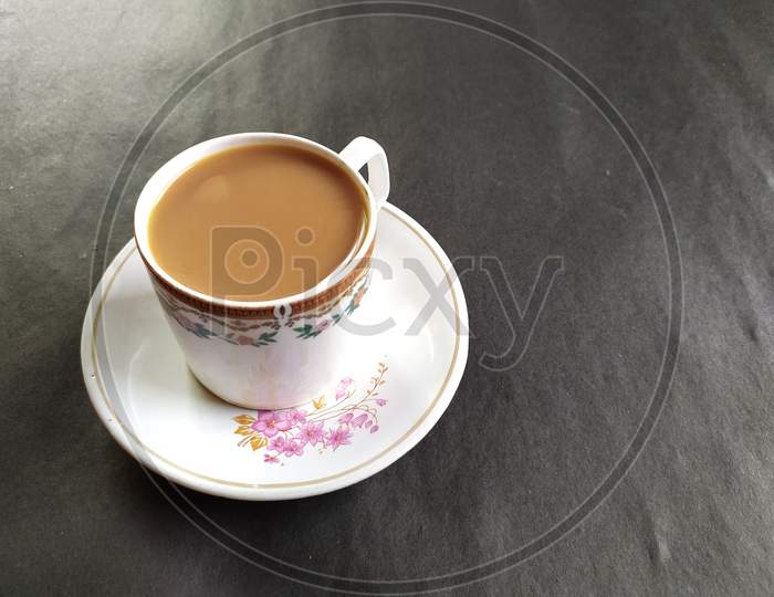 A cup of tea on plate, Black background.