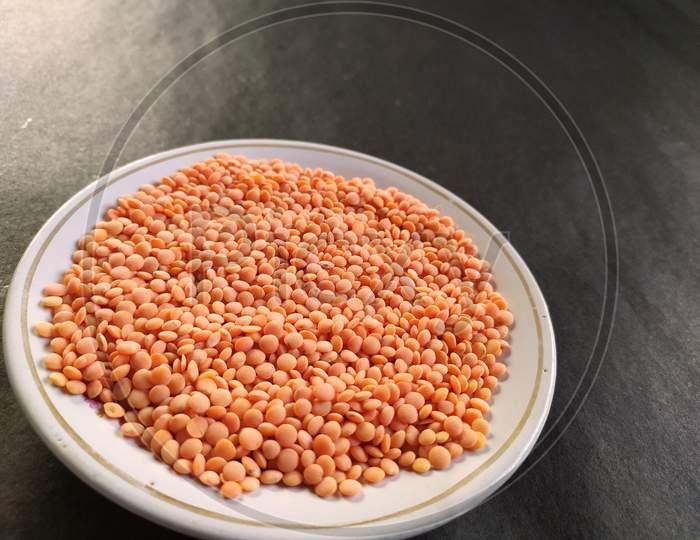 Red lentil on a plate, Black background