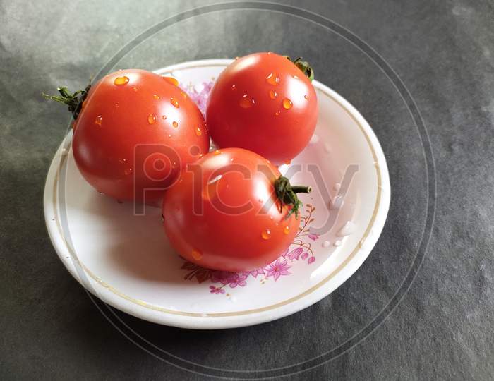 Tomatoes on plate, black background.