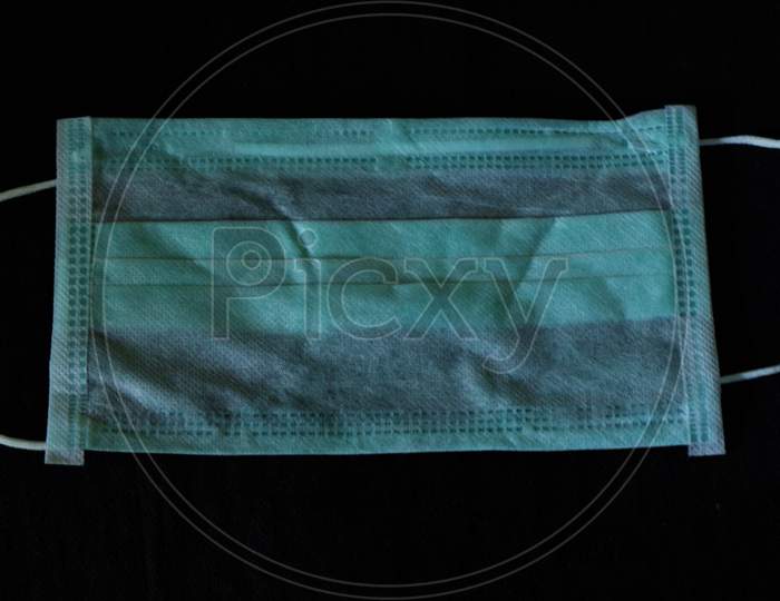 Disposable safety surgical mask on black background.